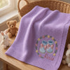 Purple Rosie Booties Blanket Draped Over Wicker Basket
