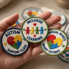 Hand Holding Three Colorful Inclusive Learning Embroidered Patches