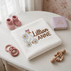 White Lillian Anne Blanket Beside Pink Booties And Storybook