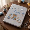 Gray Embroidered Memory Notebook Surrounded By Sewing Supplies