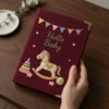 Hand Holding Maroon Rocking Horse Baby Keepsake Notebook