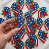 Hand Holding Patriotic Stars And Blooms Bow Patch