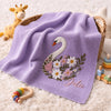Purple Julie Swan Blanket Draped Beside Colorful Nursery Toys