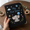 Black Personalized Baby Notebook Held Above Wooden Table