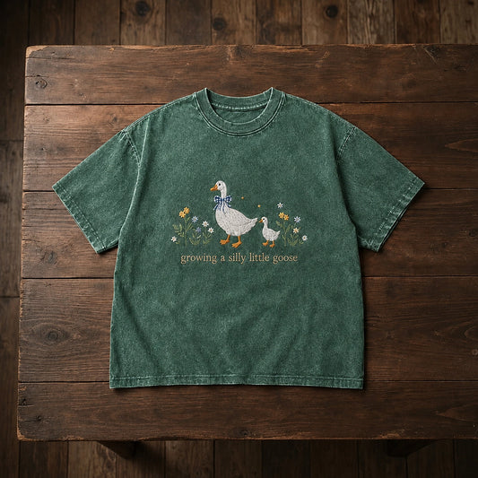 Moss Wildflower Goose Embroidered Tee Displayed On Wooden Table