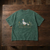 Moss Wildflower Goose Embroidered Tee Displayed On Wooden Table